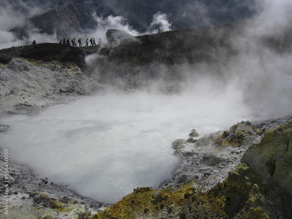 Steamy acidic hot spring with silhouettes of figures in the distance. White Island, New Zealand, 2009.