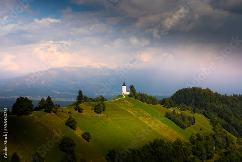 Mountain scenery with church on the mountain ridge. Colorful sunset scenery and cute Saint Primoz church with high mountains in background, Jamnik village, Slovenia, Europe