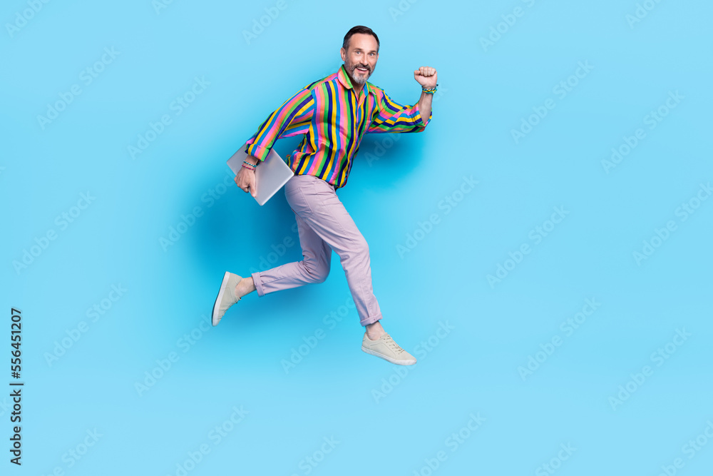 Obraz premium Full length photo of cheerful man satisfied new quality gadget raise hand fist wish you luck isolated on blue color background