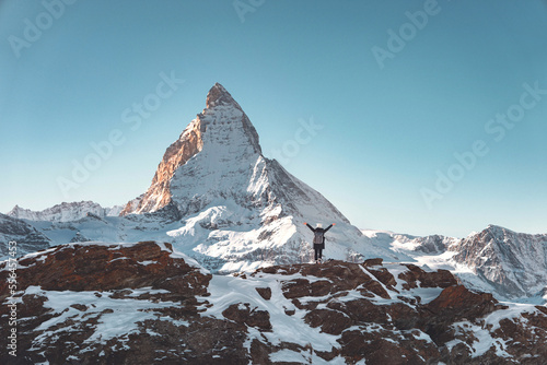 Happy hiker traveler woman with backpack enjoying in Swiss Alps with the Matterhorn in winter background, Europe travel vacation