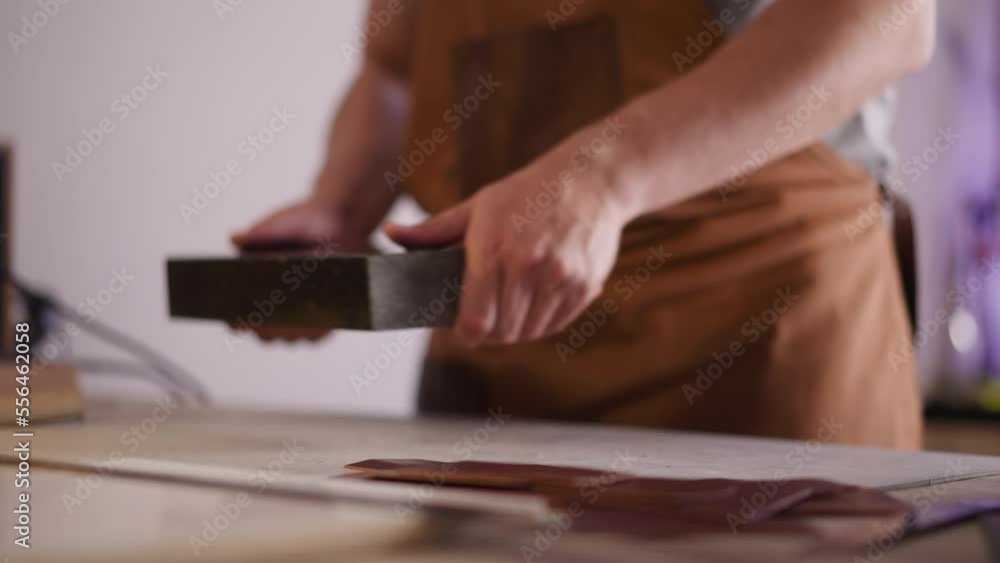 Craftsman puts stand for leather processing on table closeup. Master uses traditional tools to make original items. Professional handyman in shop Craftsman puts stand for leather processing on table closeup. Master uses traditional tools to make original items. Professional handyman in shop