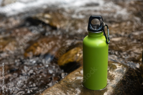 Green water bottle of the type used by outdoors people like climbers, walkers and campers on nature background.
 photo