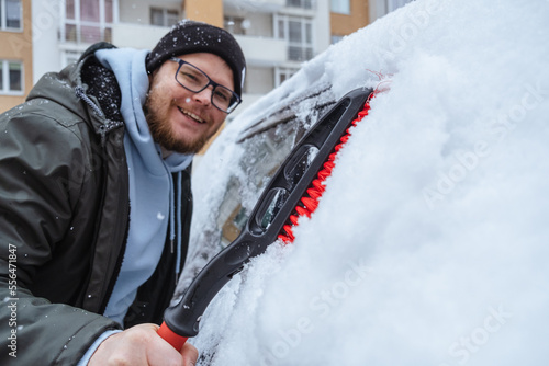 A man is cleaning a car that has been covered in snow