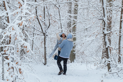 a man spins a woman in his arms in the winter forest