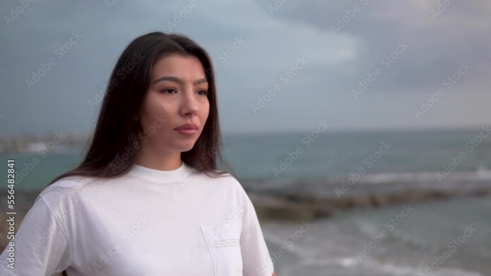 Beautiful sad woman of Asian appearance against a cloudy sky. Beautiful sad woman of Asian appearance against a cloudy sky.