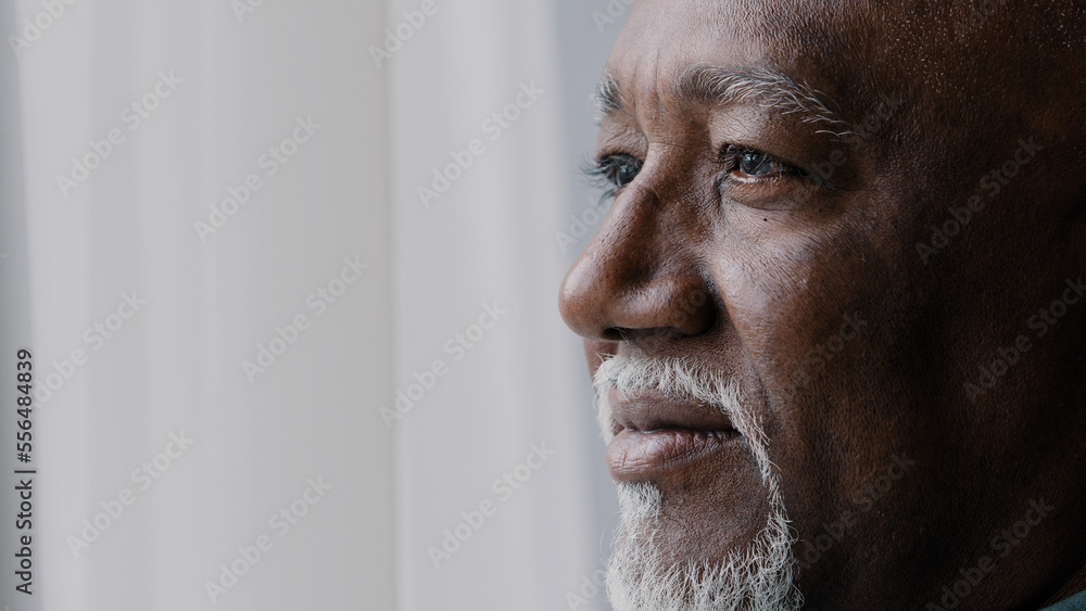 Obraz premium Close up pensive male old wrinkled face, 60s African bearded man deep in sad thoughts looking at window, elderly grandfather look away think about disability feel lonely. Nostalgia retired businessman