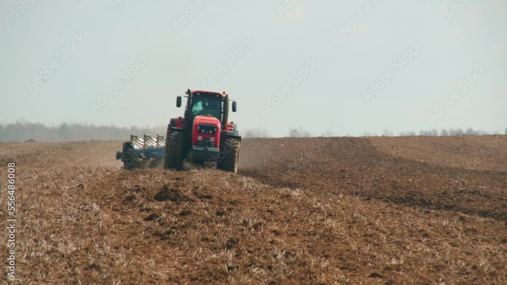 Front view of a modern energy-saturated tractor working in the field. Farmer on arable land during the spring sowing campaign. Agribusiness concept Front view of a modern energy-saturated tractor working in the field. Farmer on arable land during the spring sowing campaign. Agribusiness concept