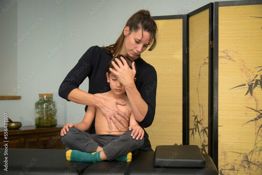 Caucasian woman practicing osteopathy on a child Caucasian woman practicing osteopathy on a child