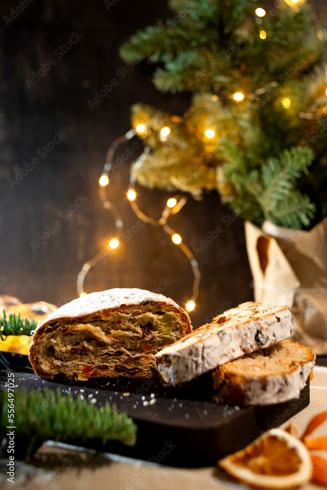 Christmas stollen on wooden background. Traditional christmas german dessert. Cake with nuts, raisins with marzipan and dried fruit on cutting board.