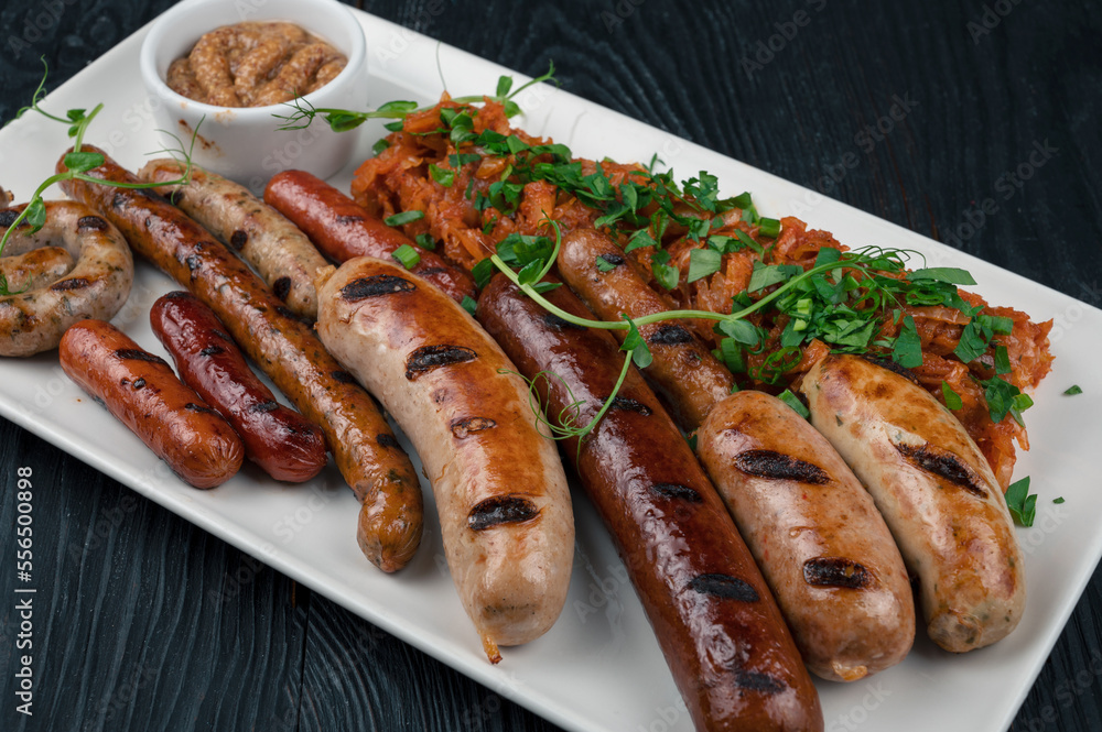 Grilled different sausage with the addition of herbs and horseradish sauce on the plate. Grilling food, bbq, barbecue concept Grilled different sausage with the addition of herbs and horseradish sauce on the plate. Grilling food, bbq, barbecue concept