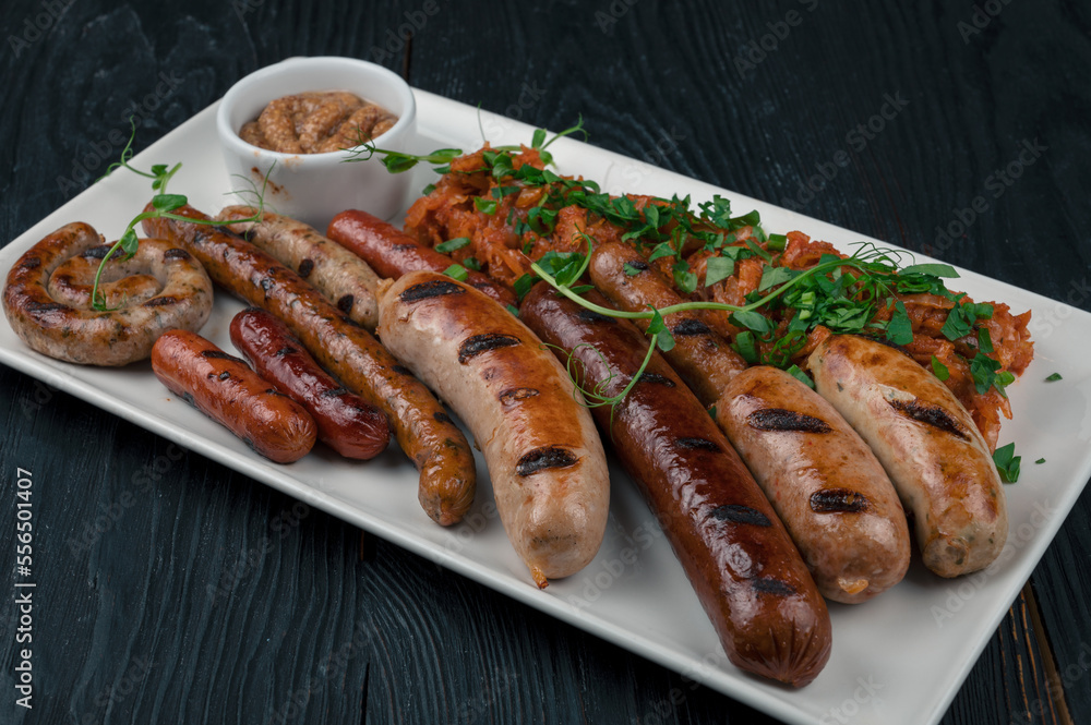 Grilled different sausage with the addition of herbs and horseradish sauce on the plate. Grilling food, bbq, barbecue concept Grilled different sausage with the addition of herbs and horseradish sauce on the plate. Grilling food, bbq, barbecue concept