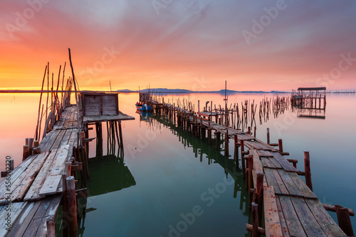 Amazing sunset on the palatial pier of Carrasqueira, Alentejo, Portugal. Wooden artisanal fishing port, with traditional boats on the river Sado. fineart color horizontal photography. photo