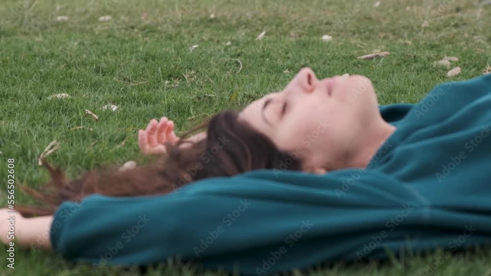 Girl laying on grass relaxing and smiling. Wind blowing in her hair Beautiful lady chilling on the ground close up. Head shot of a girl laying in the field. Girl laying on grass relaxing and smiling. Wind blowing in her hair Beautiful lady chilling on the ground close up. Head shot of a girl laying in the field.