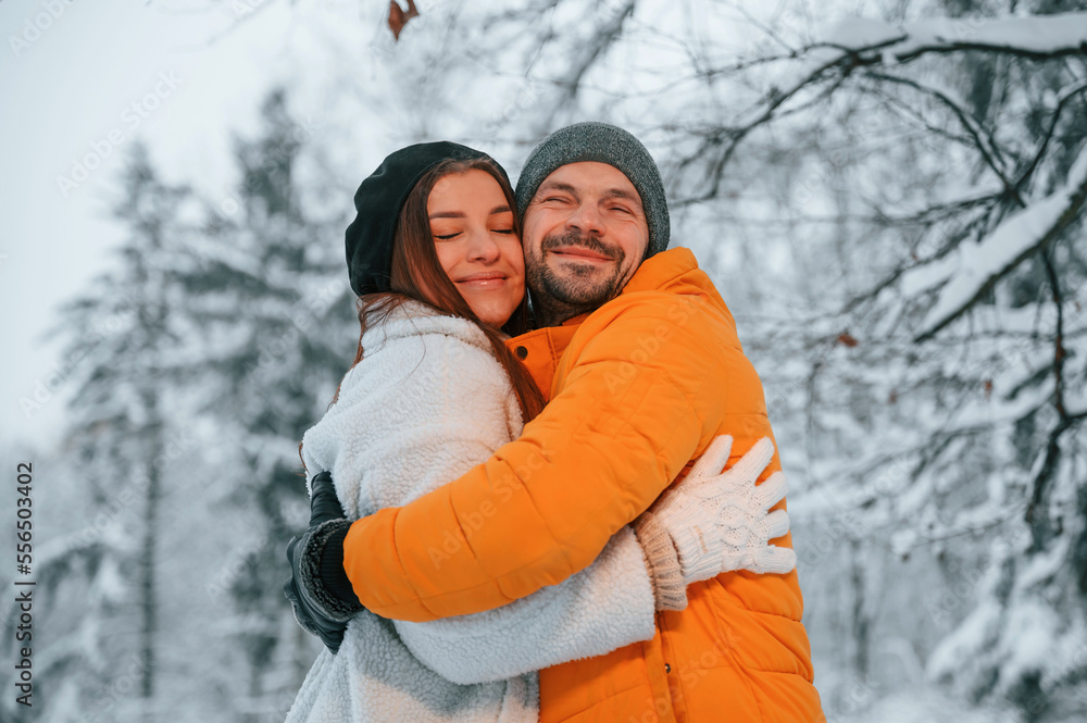 Lovely couple embracing each other while standing in the winter forest