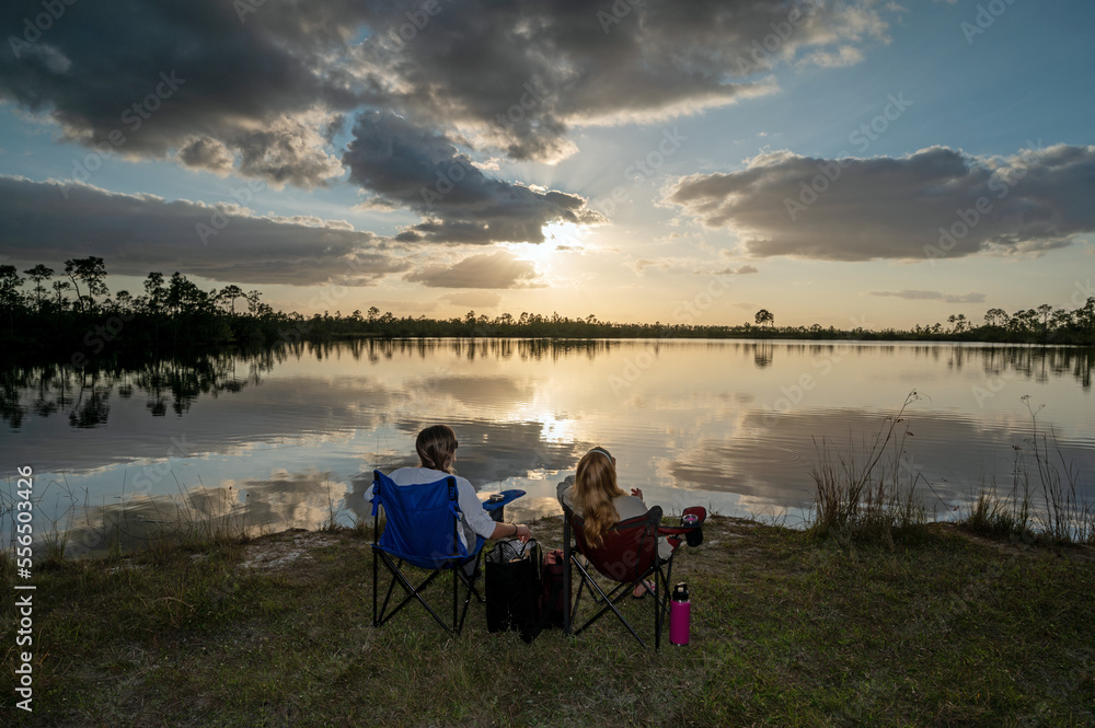 Two women in camp chairs enjoy sunset by Pine Glades Lake in Everglades National Park, Florida Two women in camp chairs enjoy sunset by Pine Glades Lake in Everglades National Park, Florida