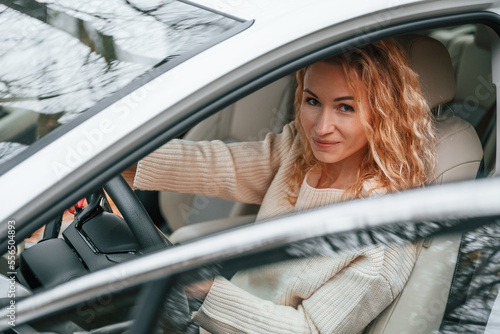 With door open. Young woman is sitting in the automobile