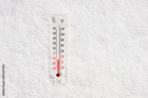 White celsius and fahrenheit scale thermometer in snow. Ambient temperature minus 11 degrees celsius