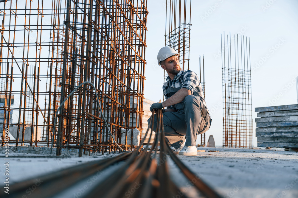 Working with metal material. Man is on the construction site at daytime Working with metal material. Man is on the construction site at daytime