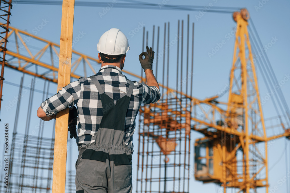 Giving orders to crane operator. Man is working on the construction site at daytime Giving orders to crane operator. Man is working on the construction site at daytime