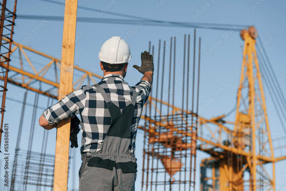 Giving orders to crane operator. Man is working on the construction site at daytime Giving orders to crane operator. Man is working on the construction site at daytime