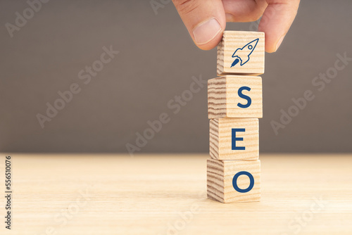 SEO or search engine optimization concept. Hand holding a wooden block with rocket icon and SEO word. Copy space