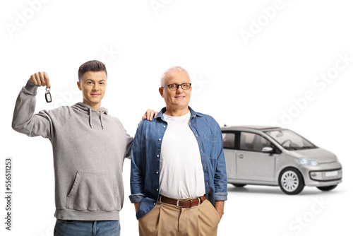 Happy father and son showing a key and standing in front of a silver car
