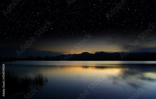 Last light of dusk over a lake surrenders to a starry sky