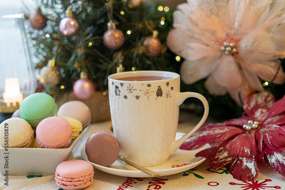 Christmas table decoration with Christmas tree, macaroons, hot tea and a pink angel Christmas table decoration with Christmas tree, macaroons, hot tea and a pink angel