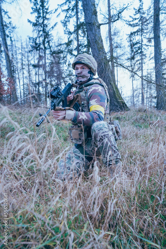 Ukrainian soldier on the front line. With an assault rifle in camouflage. Yellow tape. 