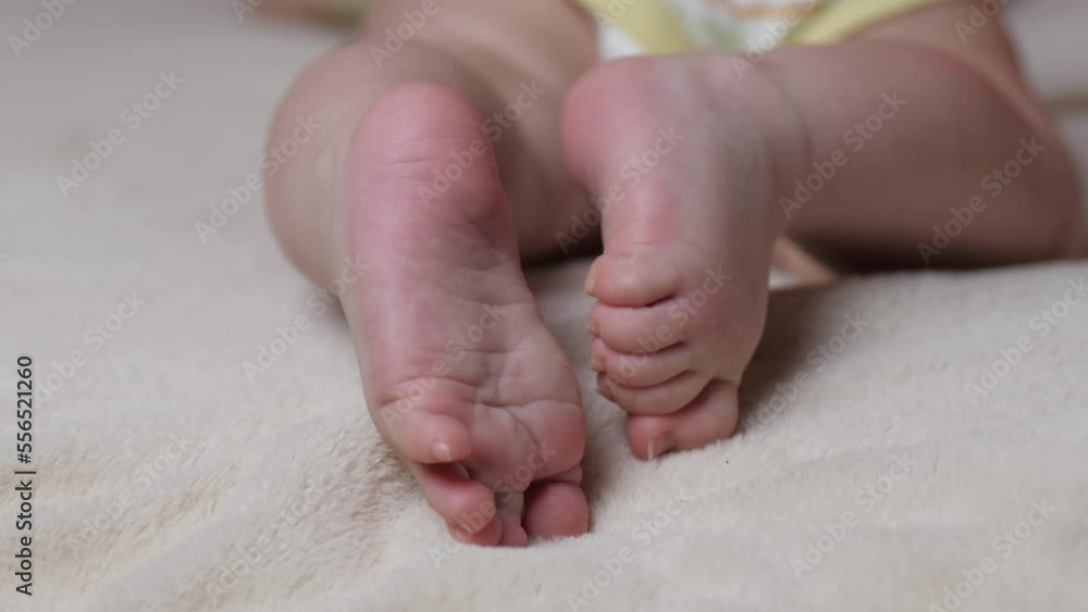 Baby feet on hands closeup. Young mother gently stroking the legs of her newborn baby. Baby feet on hands closeup. Young mother gently stroking the legs of her newborn baby.