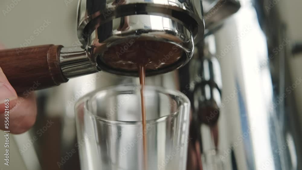 Pouring coffee stream from professional machine. Barista making double espresso, using filter holder. Pouring coffee stream from professional machine. Barista making double espresso, using filter holder.