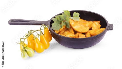 Fried potatoes in a black pig-iron frying pan and fresh vegetables on a white background with a place for the text. Top view