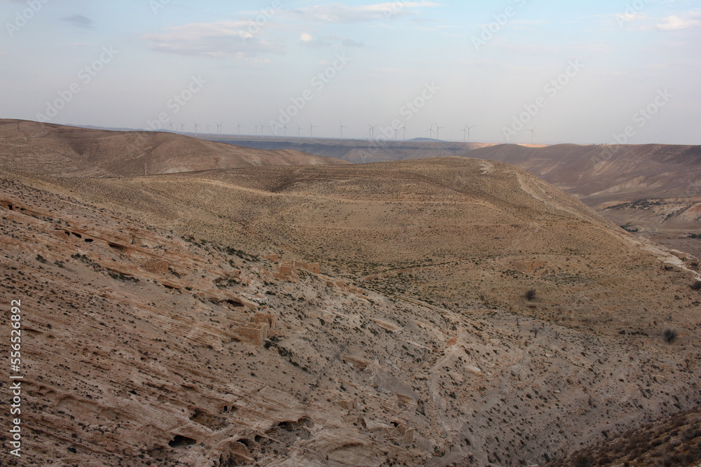 Desert landscape view of sunny rocky cliff with wind turbines in view taken from Shobak Castle, Jordan
