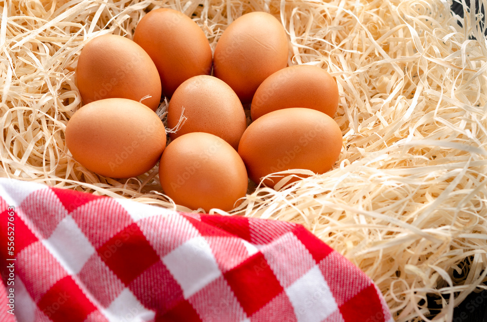 Fresh chicken eggs in a nest next to a napkin Fresh chicken eggs in a nest next to a napkin