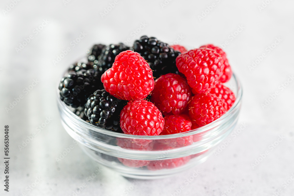 Fresh ripe organic raspberries and blackberries close-up in a glass bowl on the kitchen table Fresh ripe organic raspberries and blackberries close-up in a glass bowl on the kitchen table