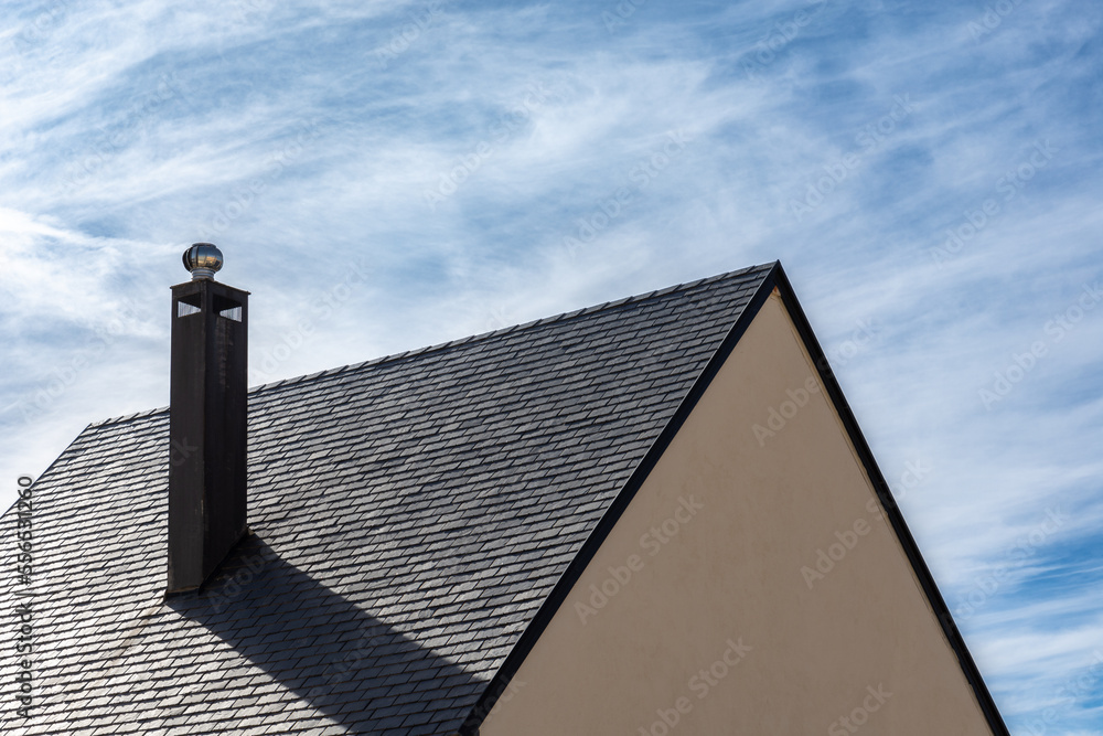 Chimney on a roof with black slate tiles