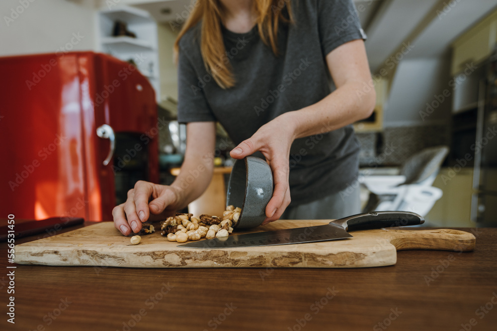 Female hands spreading hazelnuts on wooden board for chopping. Female hands spreading hazelnuts on wooden board for chopping.