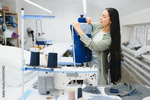 Portrait of a beautiful seamstress carrying a tape measure and working in a textile factory