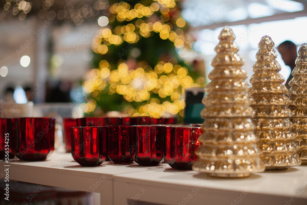 Golden glass Christmas tree and red candlesticks decorations for holiday season at home. Festive Xmas market background.
