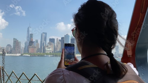 Young woman taking picture with smartphone staten island ferry magnificent views of skyscrapers in manhattan new york buildings seen from the river concept lifestyle city vacation adventu photo