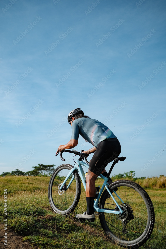 A young bearded cyclist is biking through a field A young bearded cyclist is biking through a field