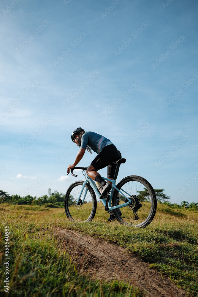 A young bearded cyclist is biking through a field A young bearded cyclist is biking through a field