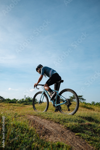 A young bearded cyclist is biking through a field © Jonathan De Guzman