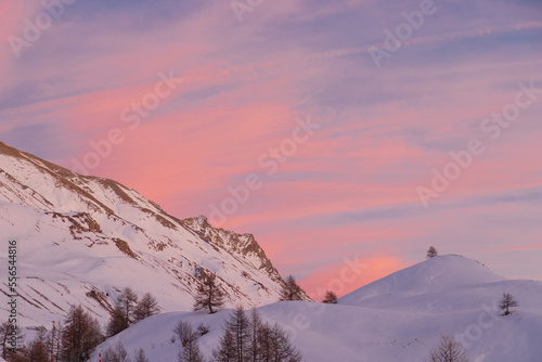 Luci rosse al crepuscolo. Sul lago gelato in mezzo alle  bianche distese di neve si specchiano i colori del cielo in alta montagna al confine tra Italia e Francia photo