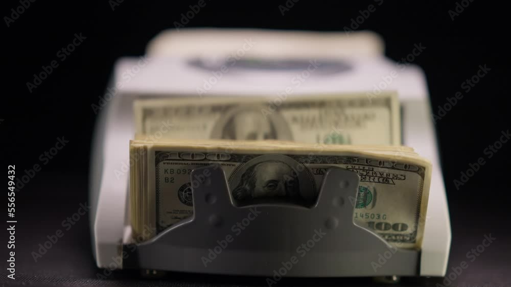 Counting machine in darkness with dollars counting in slow motion. Cash banknotes calculation with device at black background. Corruption and money laundering concept Counting machine in darkness with dollars counting in slow motion. Cash banknotes calculation with device at black background. Corruption and money laundering concept