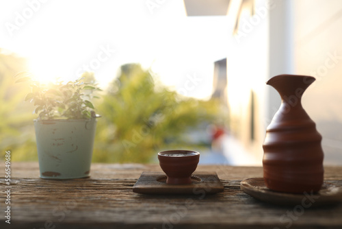Fotografi Tea cup and brown earthenware tea pot on wooden table