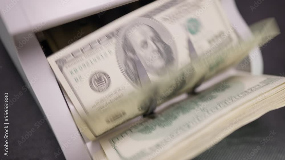 High angle view close-up cash hundred dollars counting in device in slow motion. Banknotes calculating in counting machine in darkness. Finance and corruption concept High angle view close-up cash hundred dollars counting in device in slow motion. Banknotes calculating in counting machine in darkness. Finance and corruption concept