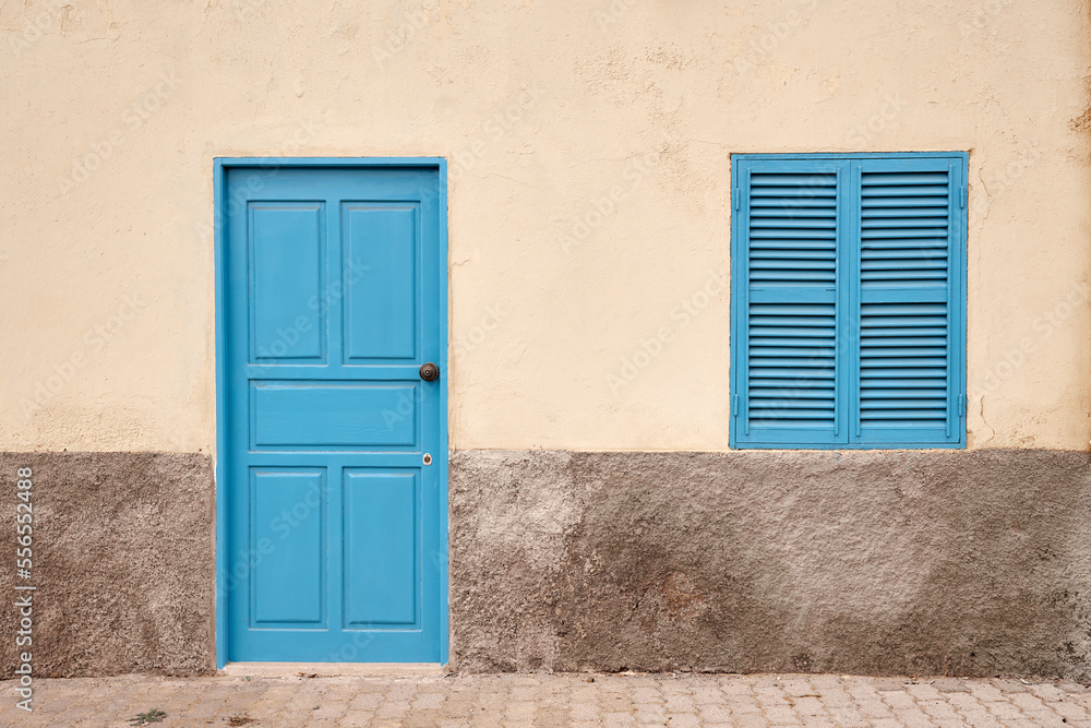 Fototapeta premium A white wall with a blue door and window.
