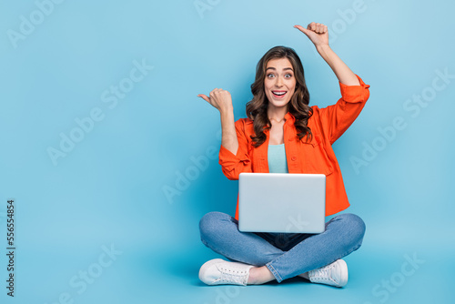 Full length photo of young attractive woman point excited impressed empty space wear trendy orange outfit isolated on blue color background © deagreez