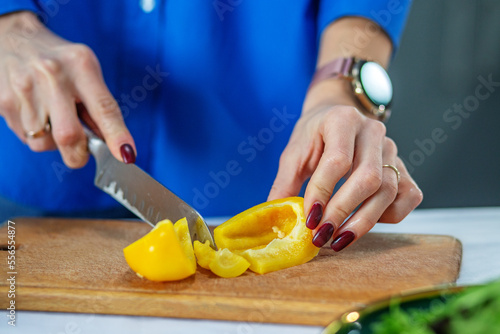 Woman cuts pepper and other vegetables with knife. Concept of eco-frien